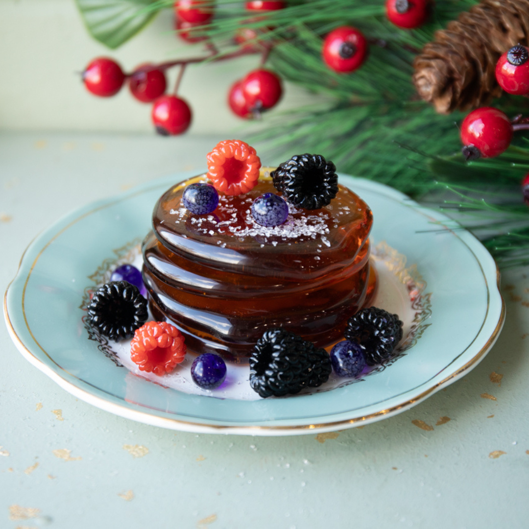 Stack of pancakes with berries on a decorative plate with a festive background